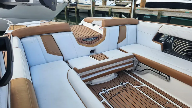 Slide: The Image of 2018 Nautique Super Air Nautique G25 interior with white and brown seating, docked at marina. - 12
