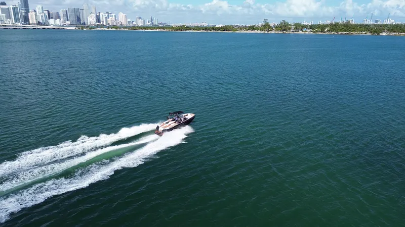 Slide: The Image of 2018 Nautique Super Air Nautique G25 cruising on open water with city skyline in background. - 33