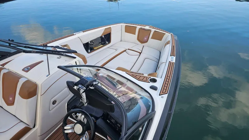 Slide: The Image of 2018 Nautique Super Air Nautique G25 boat interior with luxurious seating on calm water. - 7
