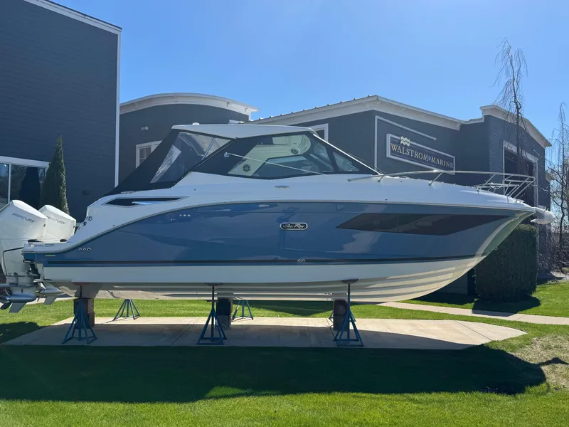 The Image of 2025 Sea Ray Sundancer 320 Coupe displayed outdoors on stands. - 0