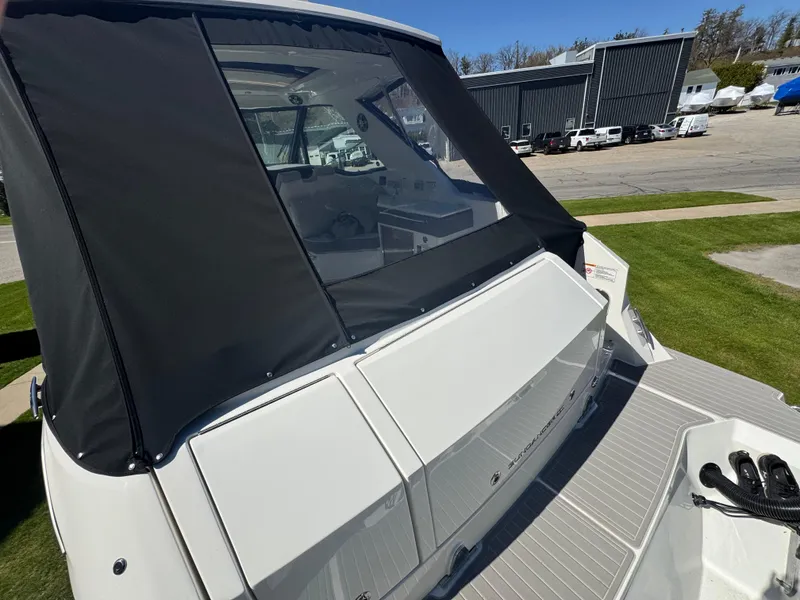 Slide: The Image of 2025 Sea Ray Sundancer 320 Coupe, rear view with black canopy, docked outdoors. - 11