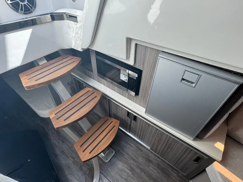 Slide: The Image of Interior of 2025 Sea Ray Sundancer 320 Coupe with wooden steps, microwave, and compact fridge. - 23