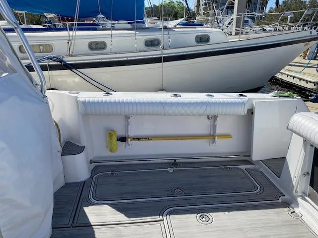 Slide: The Image of 2005 Pro-Line Express boat deck with storage and cleaning brush, docked near other boats. - 10