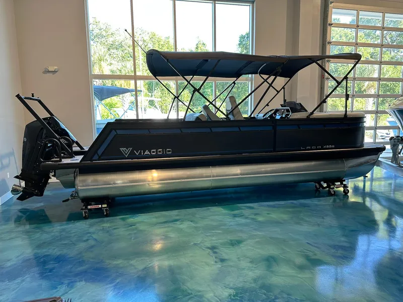 Slide: The Image of 2025 Viaggio Lago X-S pontoon boat in showroom with blue flooring. - 0