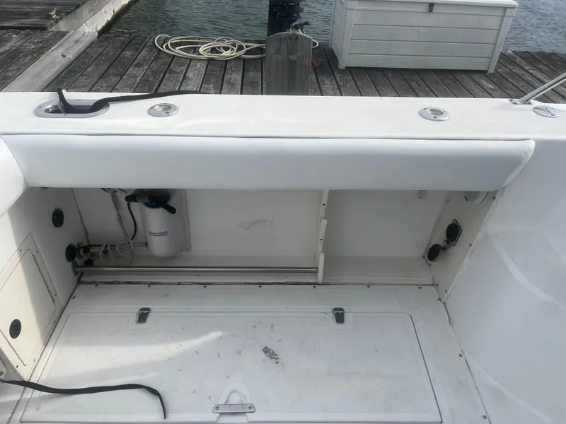 Slide: The Image of 2002 Boston Whaler 295 Conquest WA boat interior with storage compartment and dock view. - 34