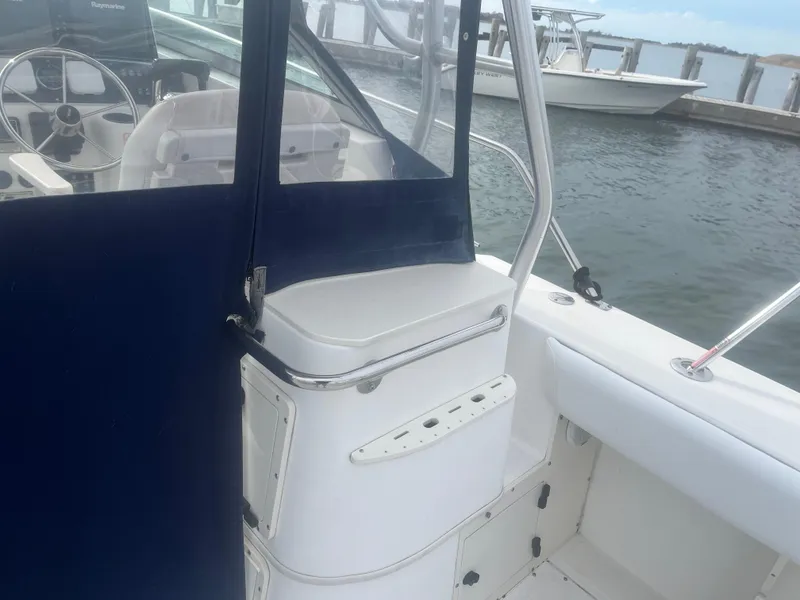 Slide: The Image of 2002 Boston Whaler 295 Conquest WA boat interior, featuring helm and seating area by the dock. - 36