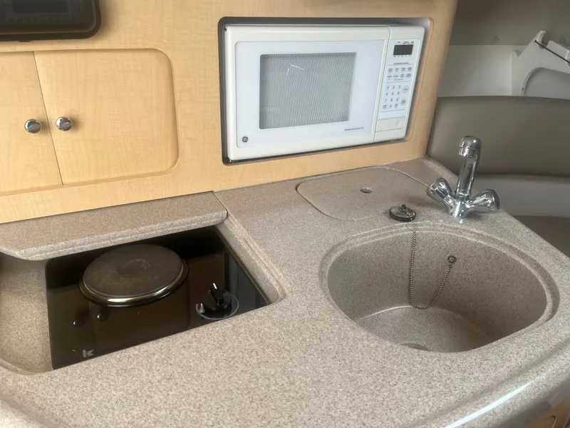 Slide: The Image of 2002 Boston Whaler 295 Conquest WA boat kitchenette with sink, stove, and microwave. - 41