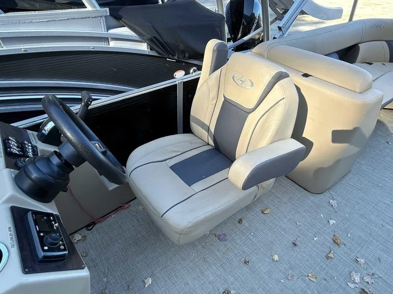 Slide: The Image of 2021 Harris Cruiser 250 boat interior with beige captain's chair and steering wheel. - 11