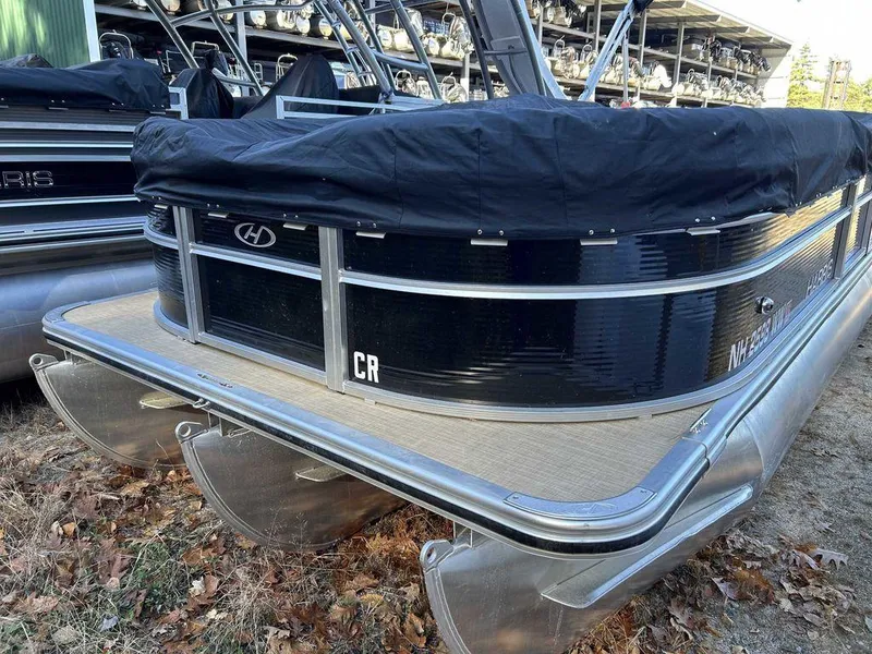 Slide: The Image of 2021 Harris Cruiser 250 pontoon boat with black cover, docked on grass. - 4
