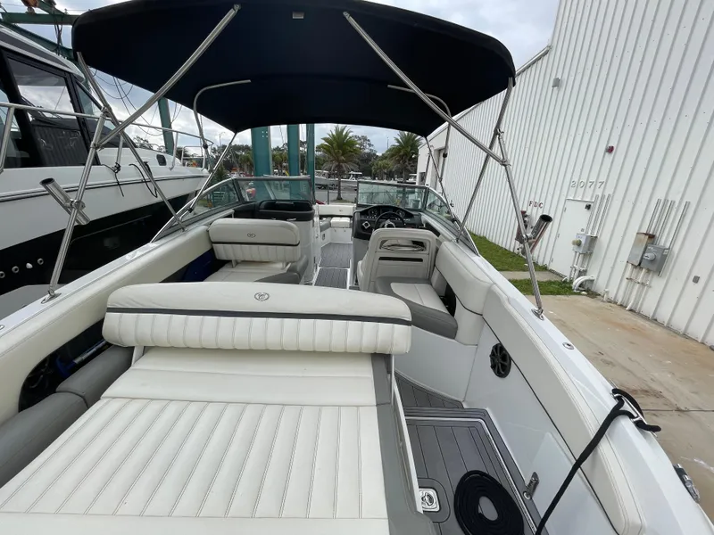 Slide: The Image of 2013 Cobalt 24SD boat with white interior and canopy, docked near a building. - 22