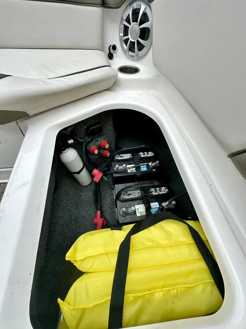 Slide: The Image of 2012 Yamaha Boats 242 Limited S storage compartment with batteries, life jackets, and fire extinguisher. - 14