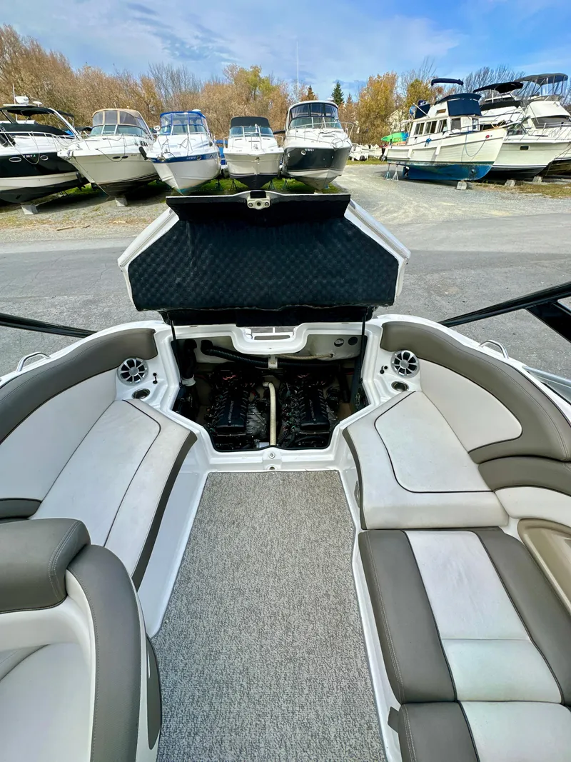 Slide: The Image of 2012 Yamaha Boats 242 Limited S interior with open engine compartment, docked among other boats. - 15