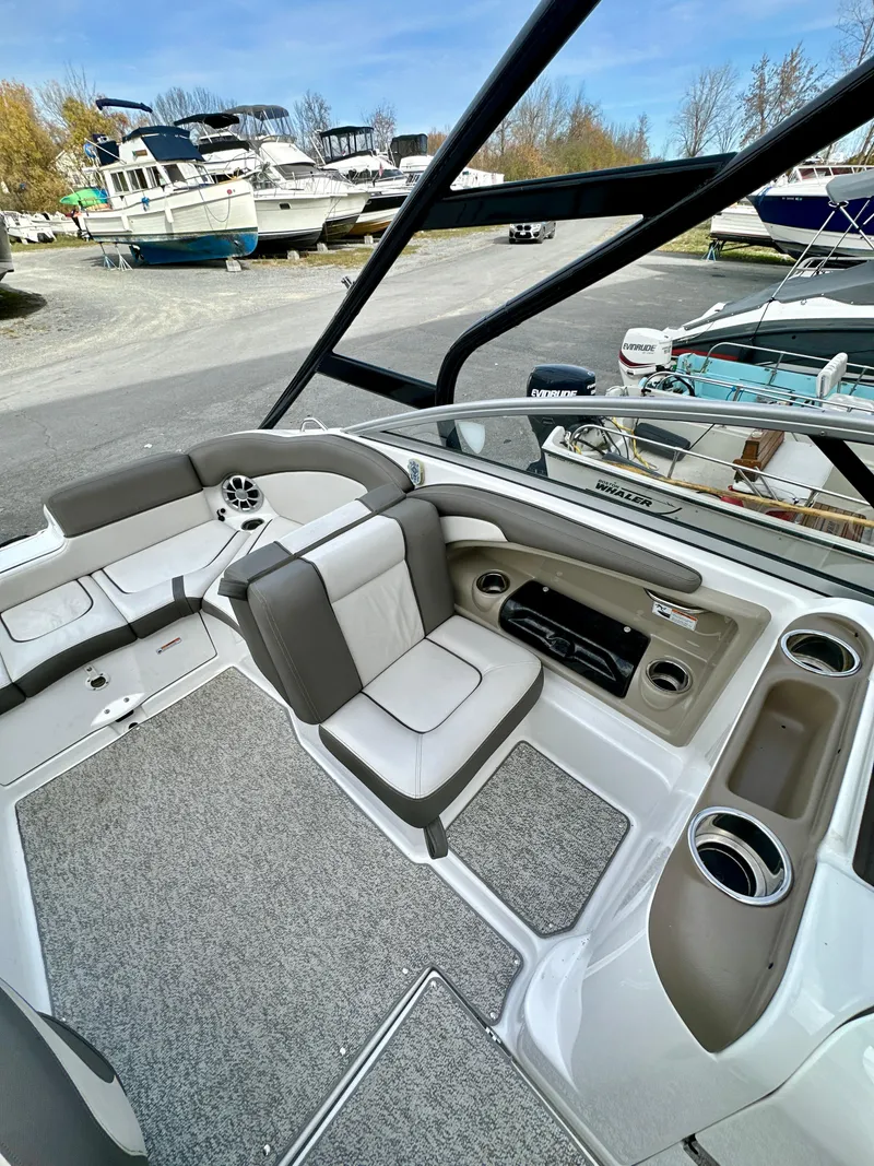 Slide: The Image of 2012 Yamaha Boats 242 Limited S interior with seating and cup holders, docked near other boats. - 7