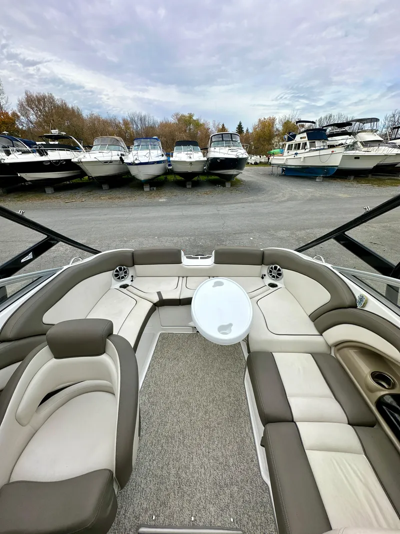 Slide: The Image of 2012 Yamaha Boats 242 Limited S interior with seating and table, docked among other boats. - 9