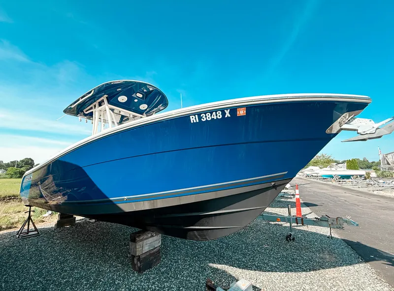 Slide: The Image of 2018 Cobia 261 boat with blue hull on dry dock under clear sky. - 0