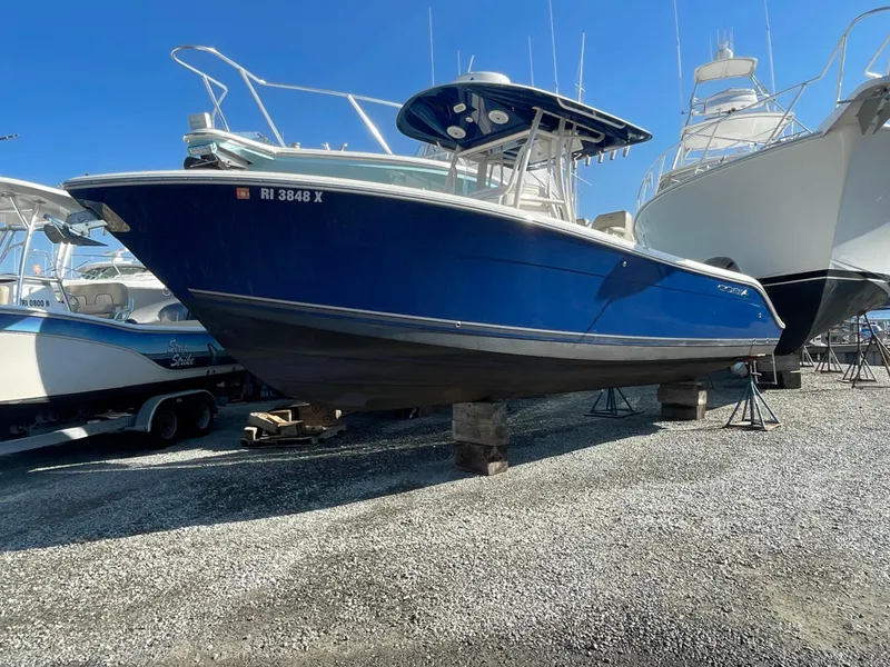 Slide: The Image of 2018 Cobia 261 boat in dry dock, blue hull, surrounded by other vessels. - 1