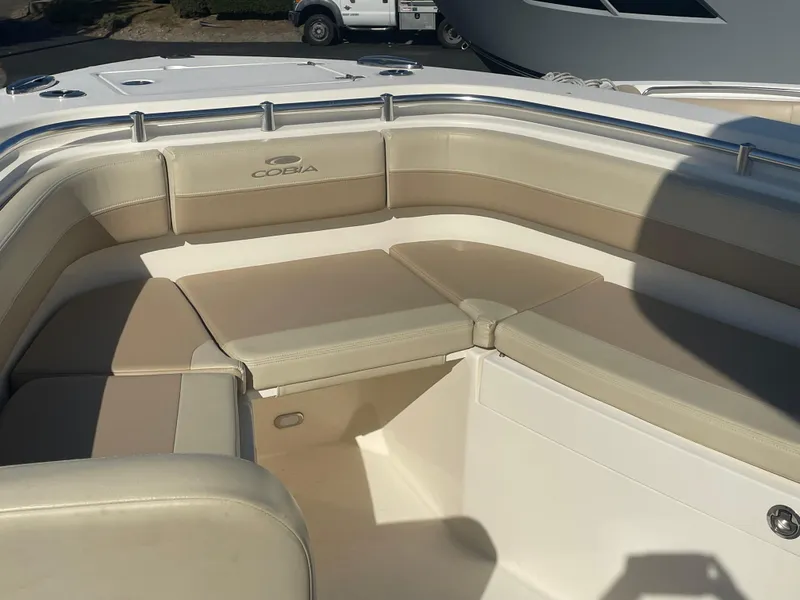 Slide: The Image of 2018 Cobia 261 boat interior with beige seating and logo. - 7