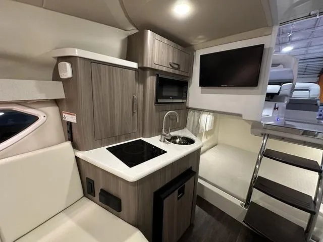 Slide: The Image of 2022 Regal 28 Express boat interior with kitchenette, sink, and TV. - 12