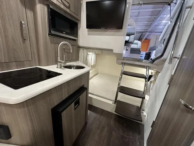 Slide: The Image of Interior of 2022 Regal 28 Express boat with kitchenette, TV, and compact sleeping area. - 14