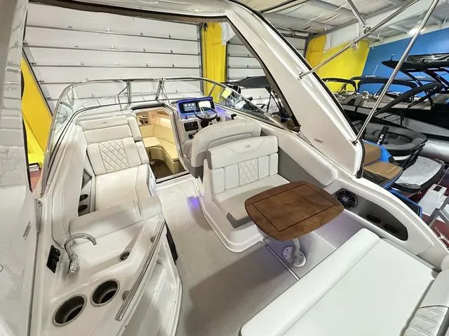 Slide: The Image of 2022 Regal 28 Express boat interior with white seating and wooden table in a showroom. - 20
