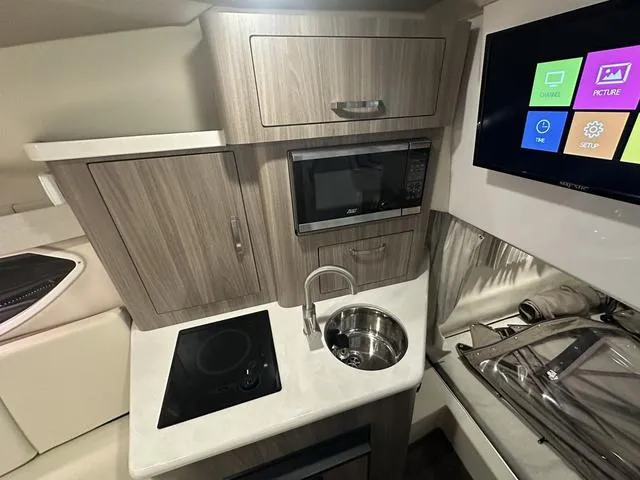 Slide: The Image of 2022 Regal 28 Express boat interior with kitchenette, microwave, sink, and modern cabinetry. - 22