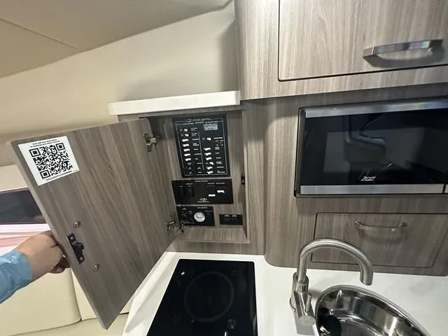 Slide: The Image of 2022 Regal 28 Express yacht kitchen with control panel, microwave, and sink. - 24