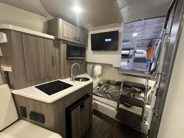 Slide: The Image of 2022 Regal 28 Express boat interior with kitchenette, sink, and TV. - 25