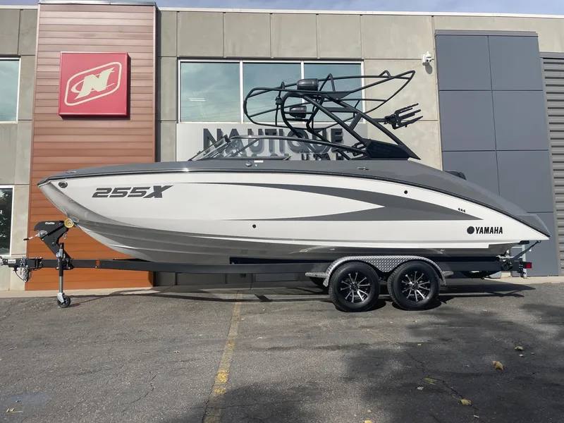 The Image of 2025 Yamaha Boats 255XE on trailer, parked outside a building. - 1