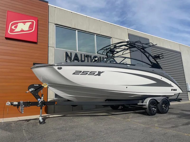 Slide: The Image of 2025 Yamaha Boats 255XE on trailer outside Nautique dealership. - 2