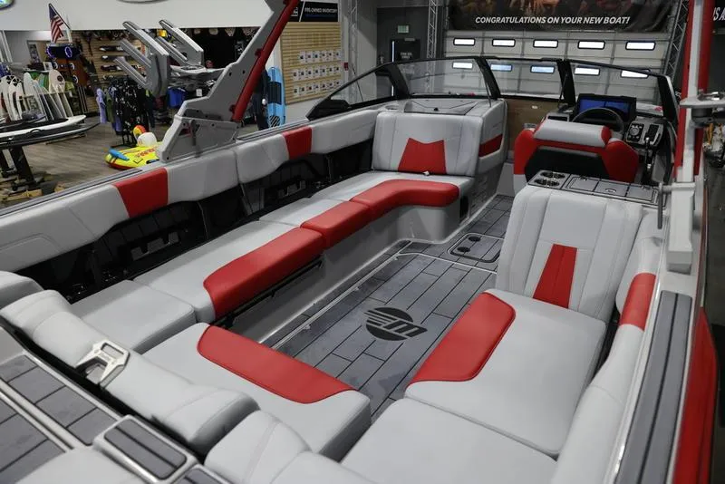 Slide: The Image of 2024 Malibu 24 MXZ boat interior with red and gray seating, showroom display. - 15