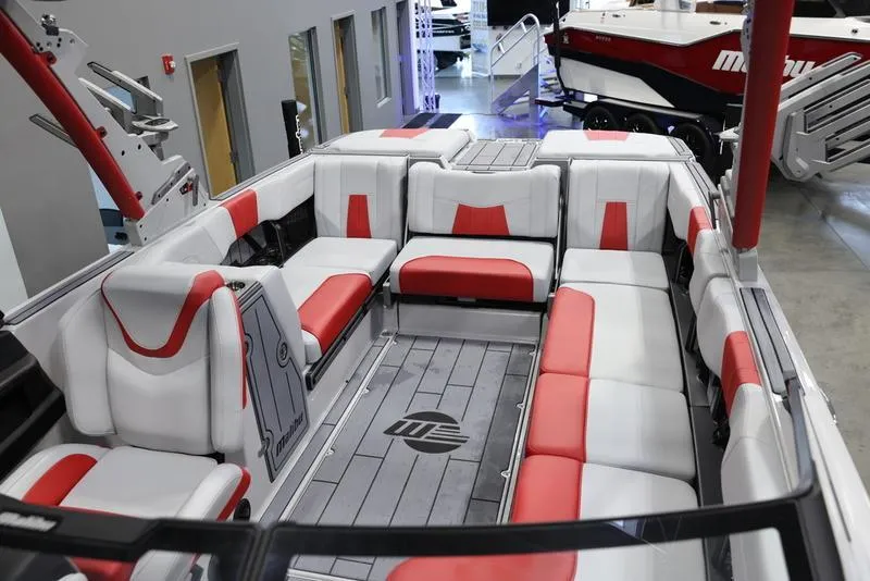 Slide: The Image of 2024 Malibu 24 MXZ boat interior with red and white seating in showroom. - 19