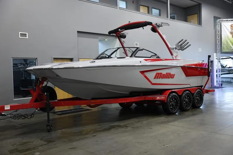 Slide: The Image of 2024 Malibu 24 MXZ boat on red trailer in showroom. - 2