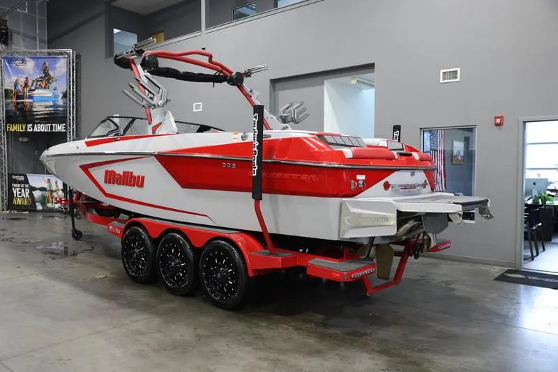 Slide: The Image of 2024 Malibu 24 MXZ boat in showroom, red and white design, on a trailer. - 23