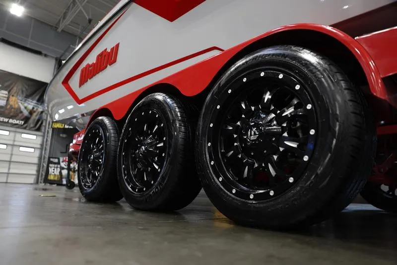 Slide: The Image of 2024 Malibu 24 MXZ boat trailer with sleek black wheels in a showroom. - 4