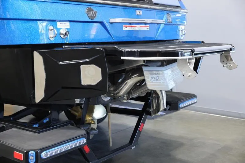 Slide: The Image of 2024 Malibu 23 LSV boat rear view with blue finish and advanced exhaust system. - 4