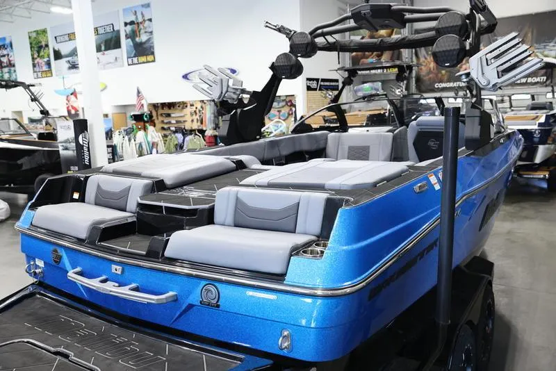 Slide: The Image of 2024 Malibu 23 LSV boat with blue exterior and luxurious seating in showroom. - 7
