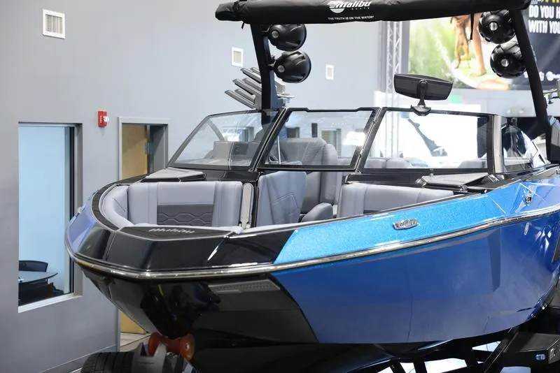 Slide: The Image of 2024 Malibu 23 LSV boat with sleek blue and black design in showroom. - 9