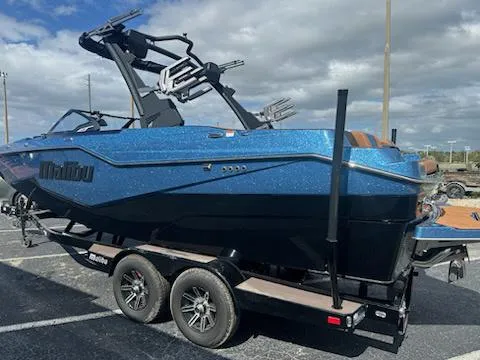 Slide: The Image of 2025 Malibu M230 boat seat with tan and blue upholstery, geometric design, and cup holders. - 2