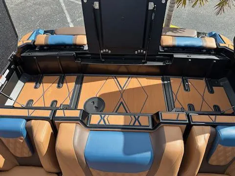 Slide: The Image of 2025 Malibu M230 boat interior with tan and blue seating, geometric flooring design. - 22