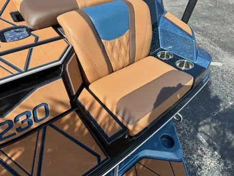 Slide: The Image of 2025 Malibu M230 boat interior with tan and blue seating. - 9