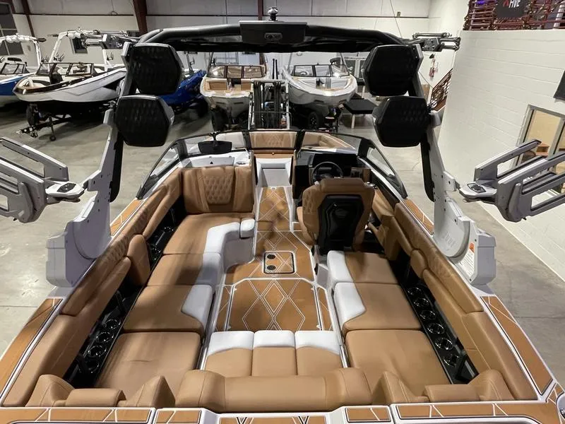Slide: The Image of 2025 Malibu M230 boat interior with tan and white seating, advanced audio system, and spacious layout. - 12