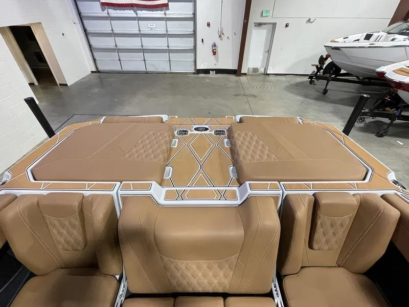 Slide: The Image of 2025 Malibu M230 boat interior with tan leather seating in a showroom. - 17