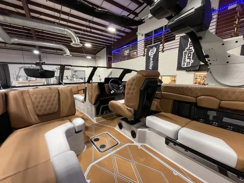 Slide: The Image of 2025 Malibu M230 boat interior with luxurious brown and white seating in a showroom. - 19