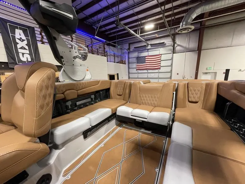Slide: The Image of 2025 Malibu M230 boat interior with tan leather seats in a warehouse setting. - 21