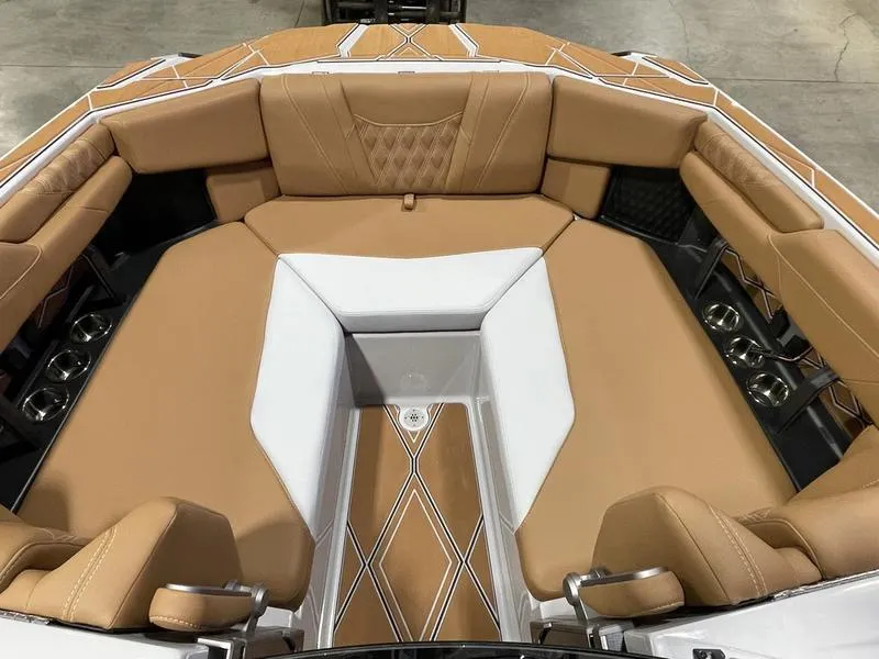 Slide: The Image of 2025 Malibu M230 boat interior with tan and white seating, diamond stitching, and cup holders. - 25