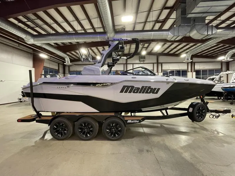 Slide: The Image of 2025 Malibu M230 boat on trailer in indoor showroom. - 6