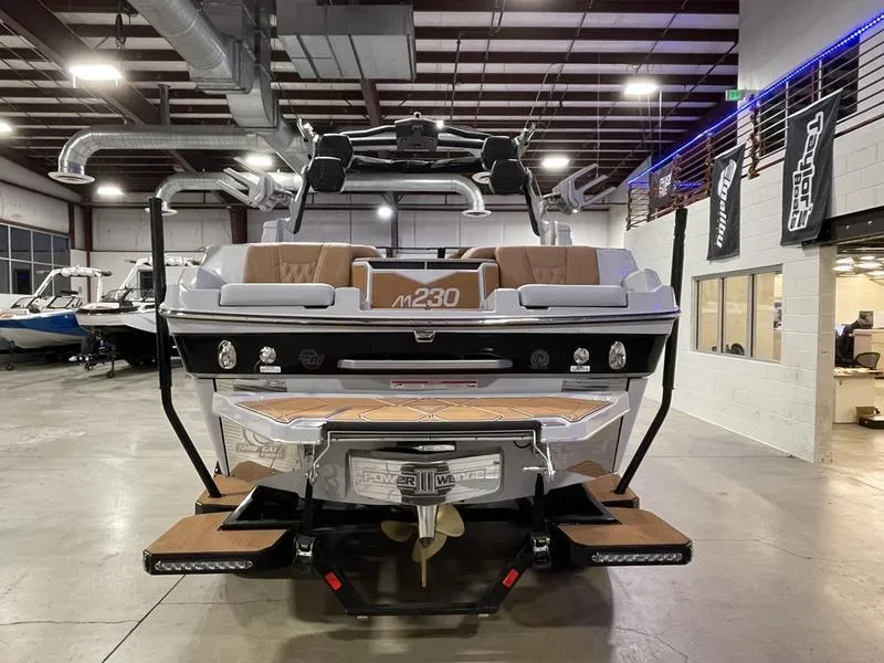 Slide: The Image of 2025 Malibu M230 boat in showroom, rear view with sleek design and modern features. - 8