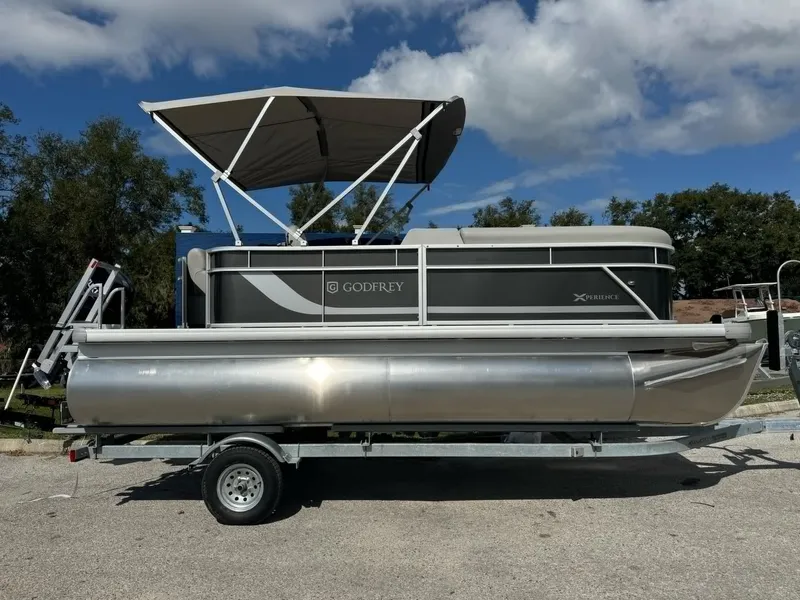 The Image of 2025 Sweetwater 1886 CX pontoon boat with canopy on trailer, parked outdoors. - 0
