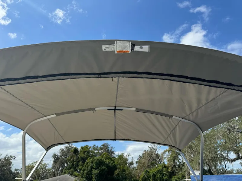 Slide: The Image of Sweetwater 1886 CX 2025 boat canopy under blue sky and trees. - 2