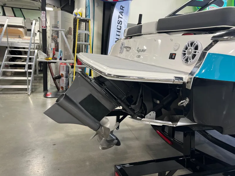 Slide: The Image of 2025 Regal LS2 Surf boat in showroom, rear view with propeller and swim platform. - 3